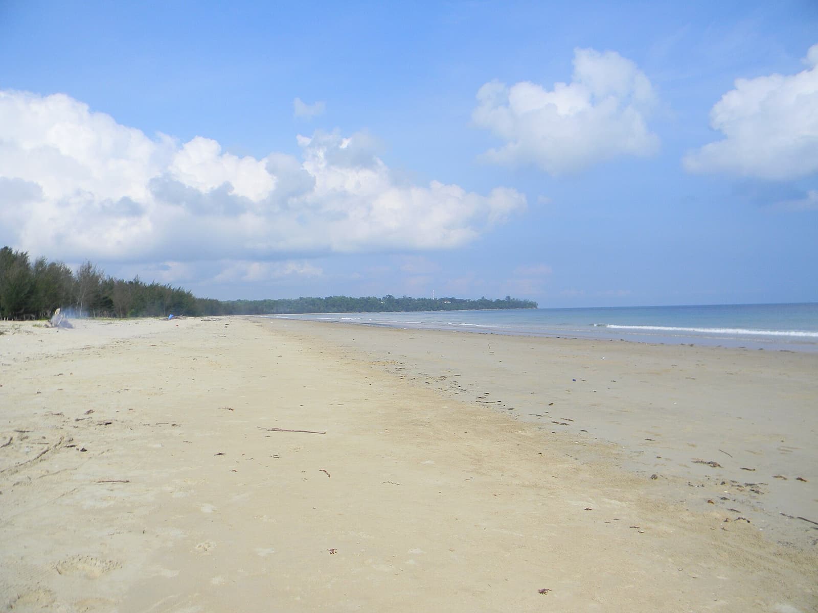 The wide, empty sand of Muara Beach under a blue sky